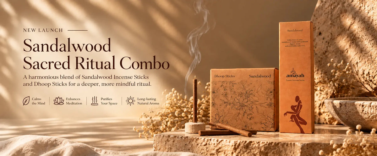 Sandalwood Sacred Ritual Combo incense sticks and Dhoop sticks packaging displayed on stone blocks with dried flowers and a smoky incense stick in a warm, sunlit setting.